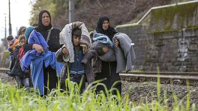 Refugiados caminan por las vías del tren en la frontera entre Austria y Eslovenia en Spielfeld