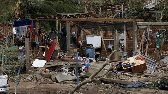 Una niña mira su casa, destrozada por el huracán Patricia