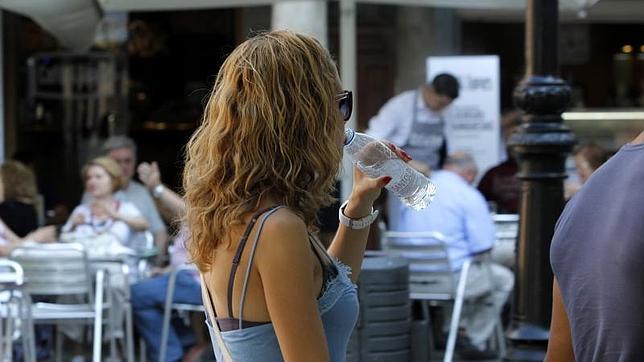 Una joven bebe agua en el centro de Toledo