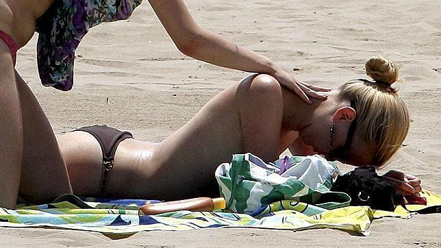 Una joven con crema solar por la espalda