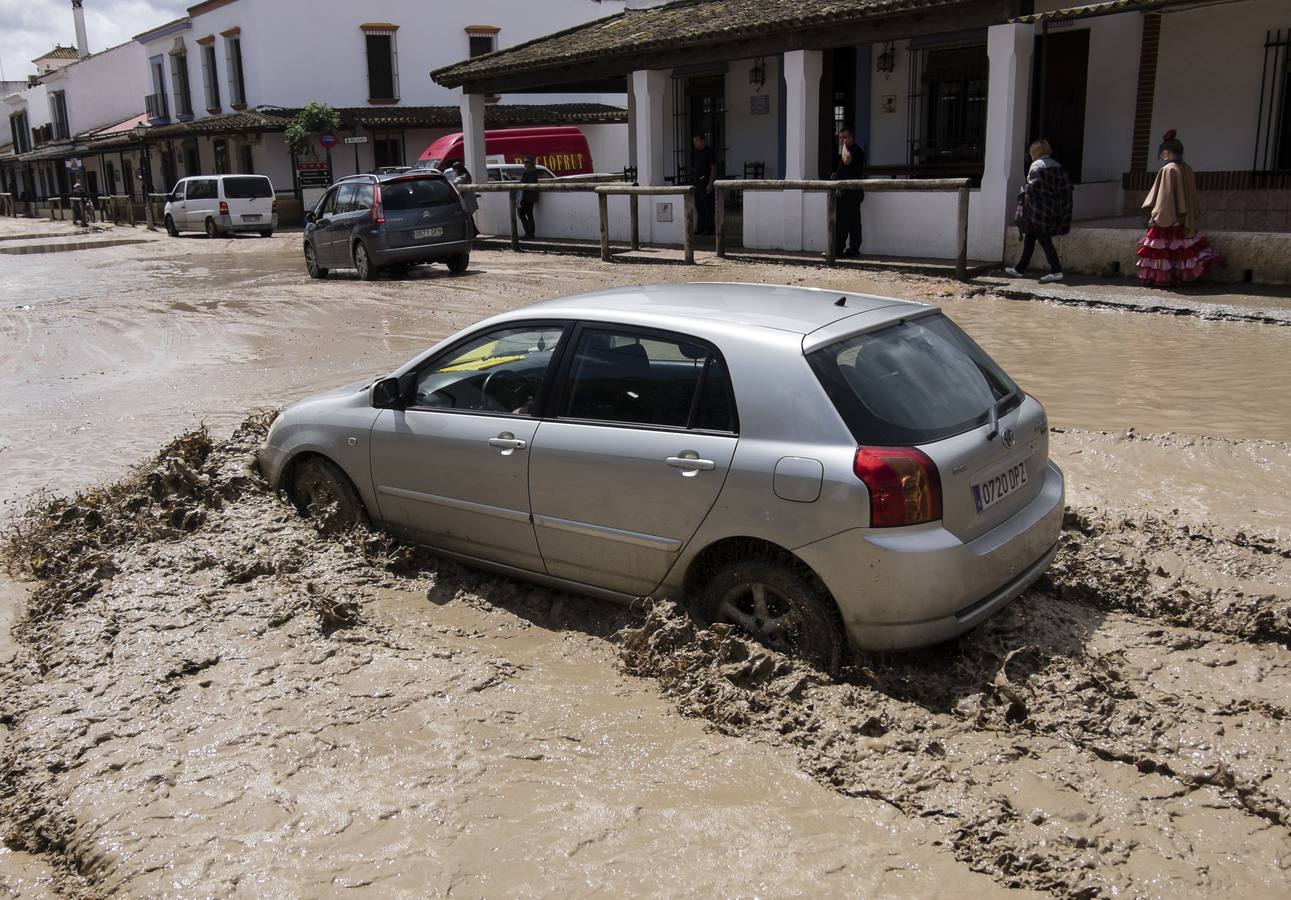 Un vehiculo transita por una calle de la aldea almonteña de El Rocio (Huelva), que se encuentra inundada a causa de las lluvias de los últimos días