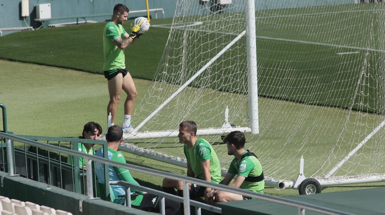 En primer término, los jugadores del Betis charlan antes de que comience el entrenamiento; por detrás, Aitor Ruibal con los guantes de portero