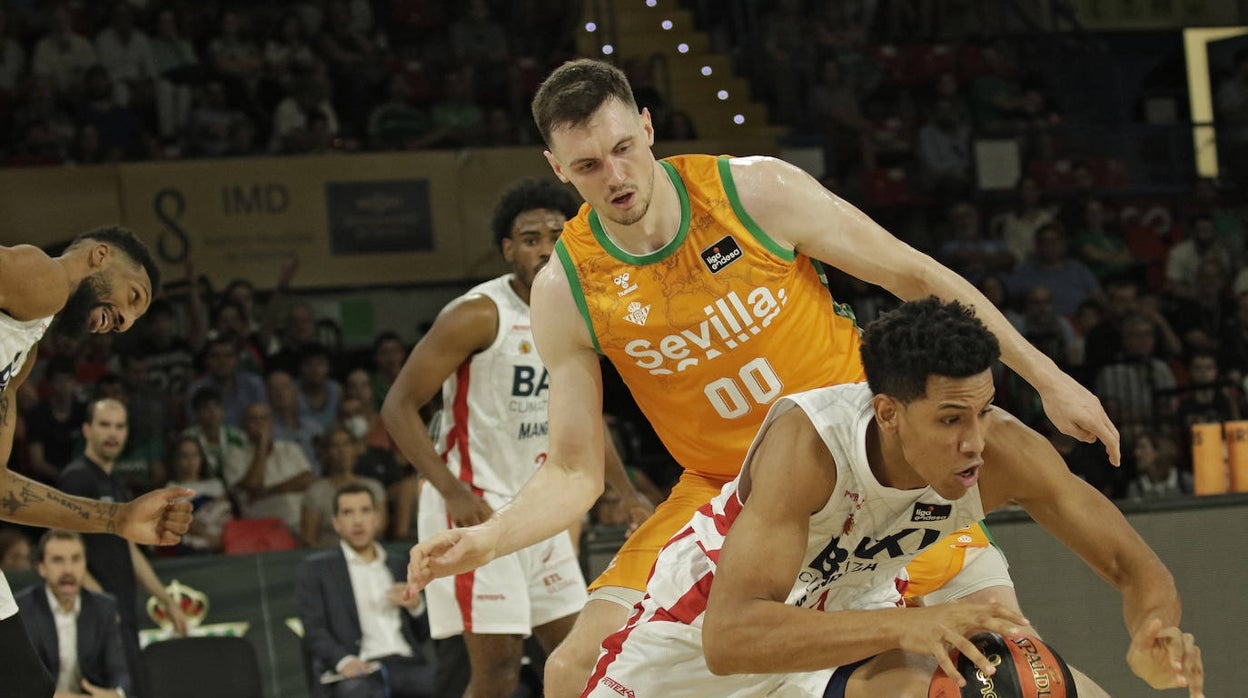 Tyson Pérez, con la pelota controlada y defendido por Kurucs en el Betis Baloncesto - BAXI Manresa de la presente temporada en San Pablo