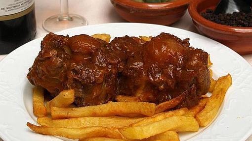 Un plato de rabo de toro acompañado con patatas fritas