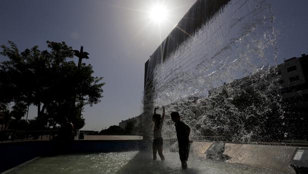 Dos niños se bañan en una fuente del Vial Norte de CórdobA este domingo