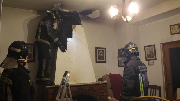 Bomberos revisan la chimenea donde se originó el incendio en el hogar de dos ancianos de Baena