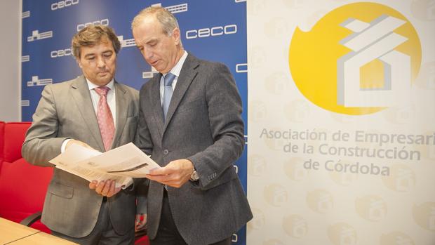 El secretario general de Construcor y su presidente observan un informe antes de una comparecencia