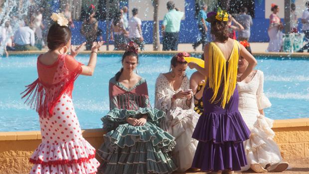 Algunas chicas descansan junto a la fuente de la portada del recinto ferial