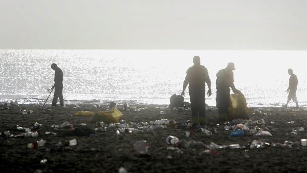 Operarios de limpieza en la playa tras una noche de San Juan