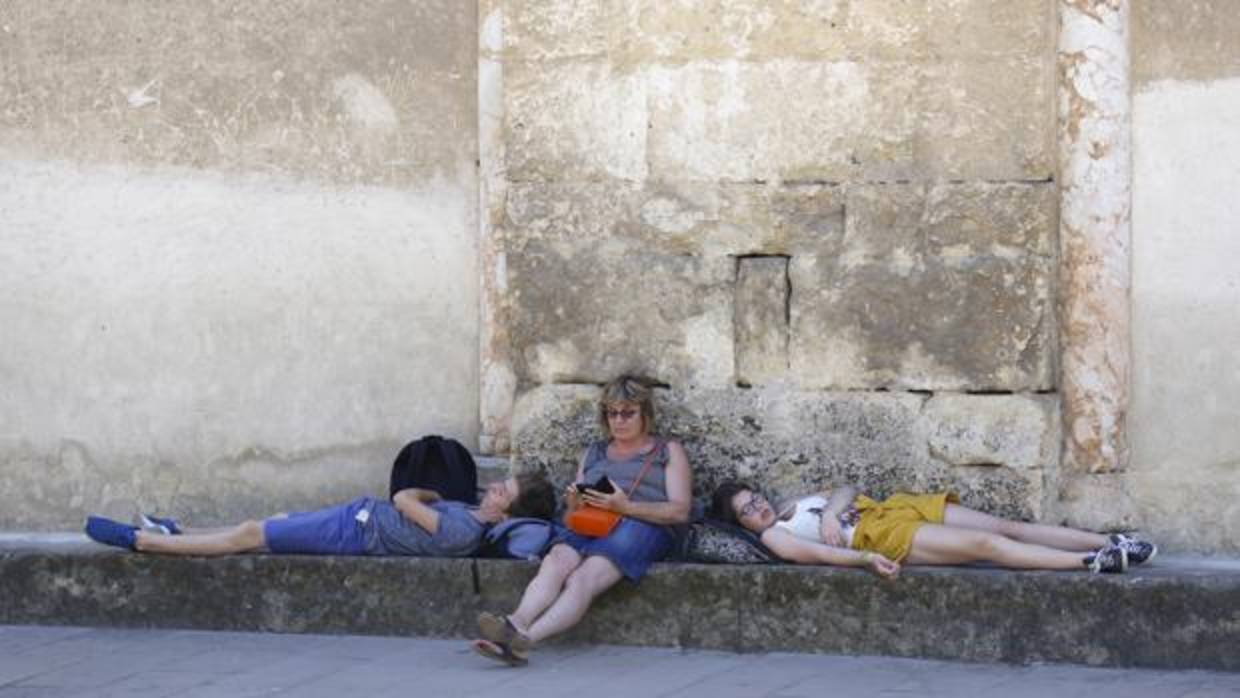 Tres personas descansan en verano en el Patio de los Naranjos de la Mezquita-Catedral de Córdoba
