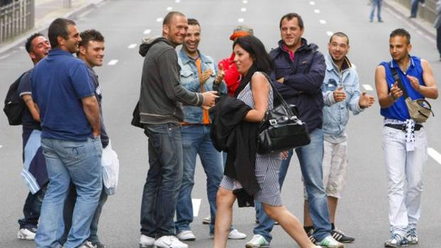 Una mujer pasa por delante de un grupo de hombre por la calle