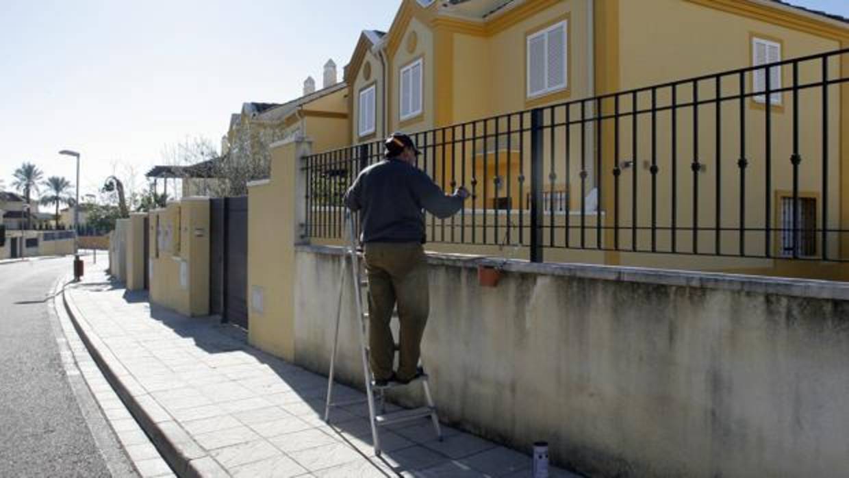 Un hombre pinta la reja de una casa en la Carrera del Caballo
