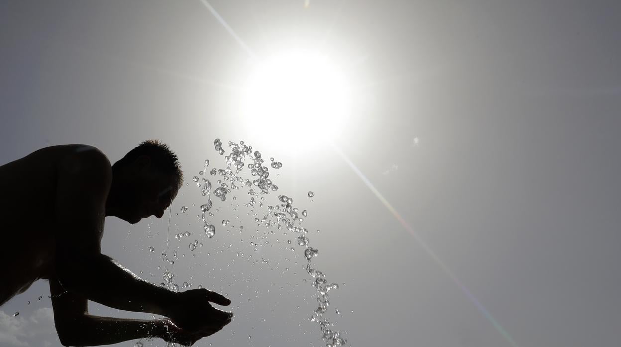 Un hombre se refresca en una fuente de Córdoba