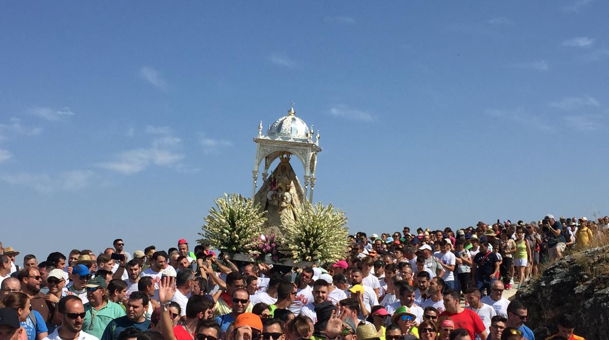 Las andas de la Virgen de la Sierra entre una multitud en las primeras curvas del descenso hacia Cabra