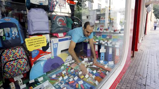 Un empleado de una tienda de material escolar coloca el escaparate