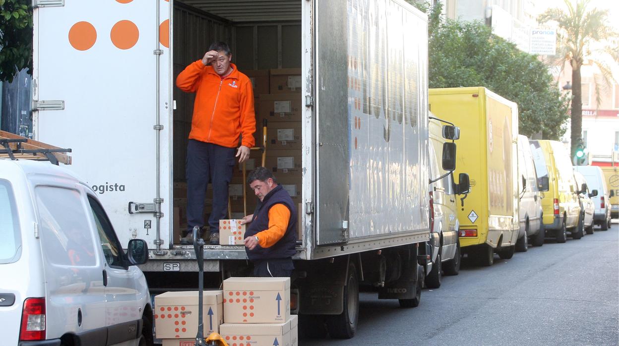 Dos trabajadores descargan mercancías de una furgoneta en el centro de Córdoba