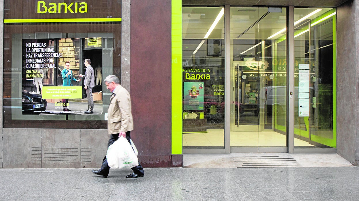 Un hombre pasa frente a una oficina de una entidad bancaria