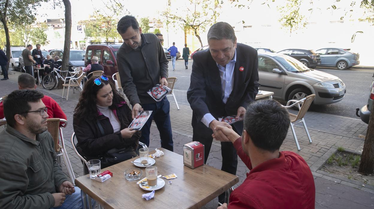 Luis Planas entrega propaganda electoral a un grupo de personas que desayuna en el Guadalquivir