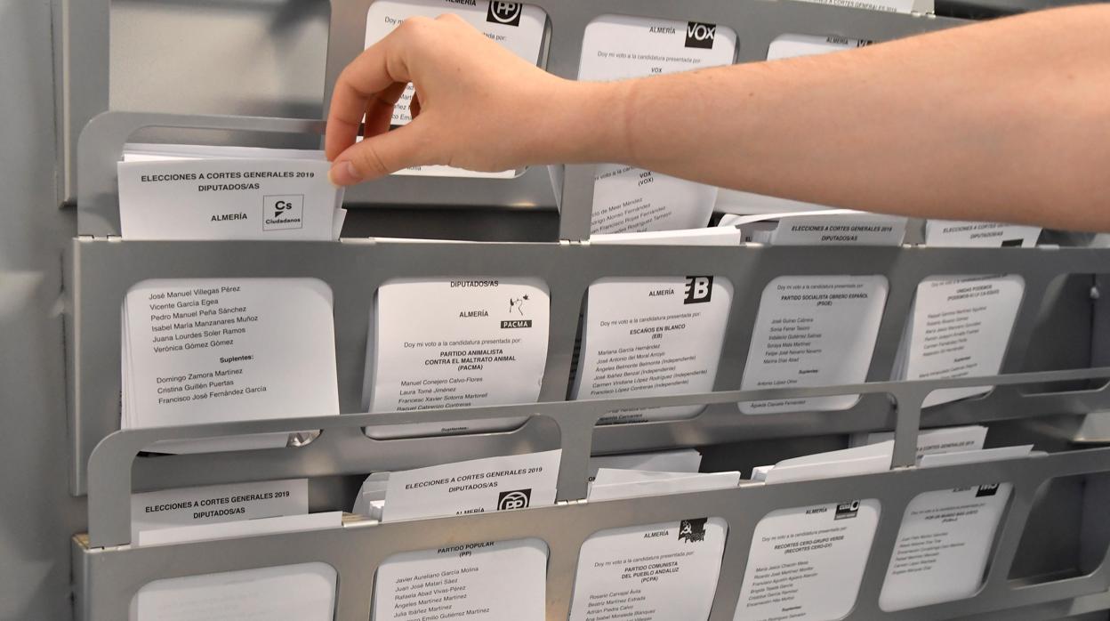 na persona elige su papeleta electoral en una cabina habilitada para ello en el C.E.I.P Nueva Almería de la capital almeriense