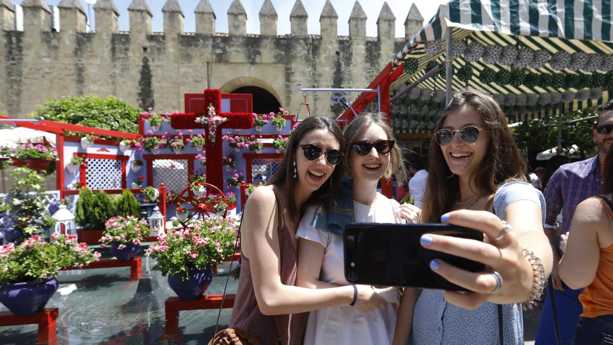 Tres jóvenes se hacen una fotografía en una Cruz de Mayo