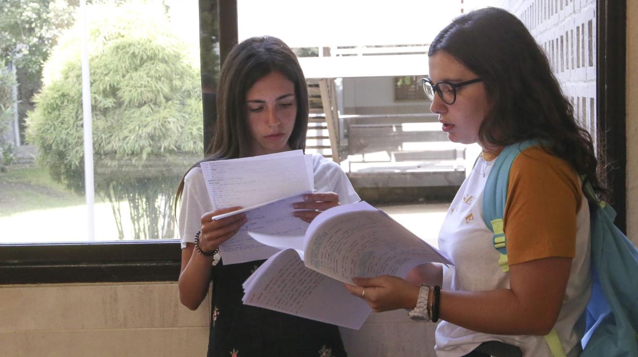 Dos esrtudiantes repasan apuntes en el pasillo de su centro