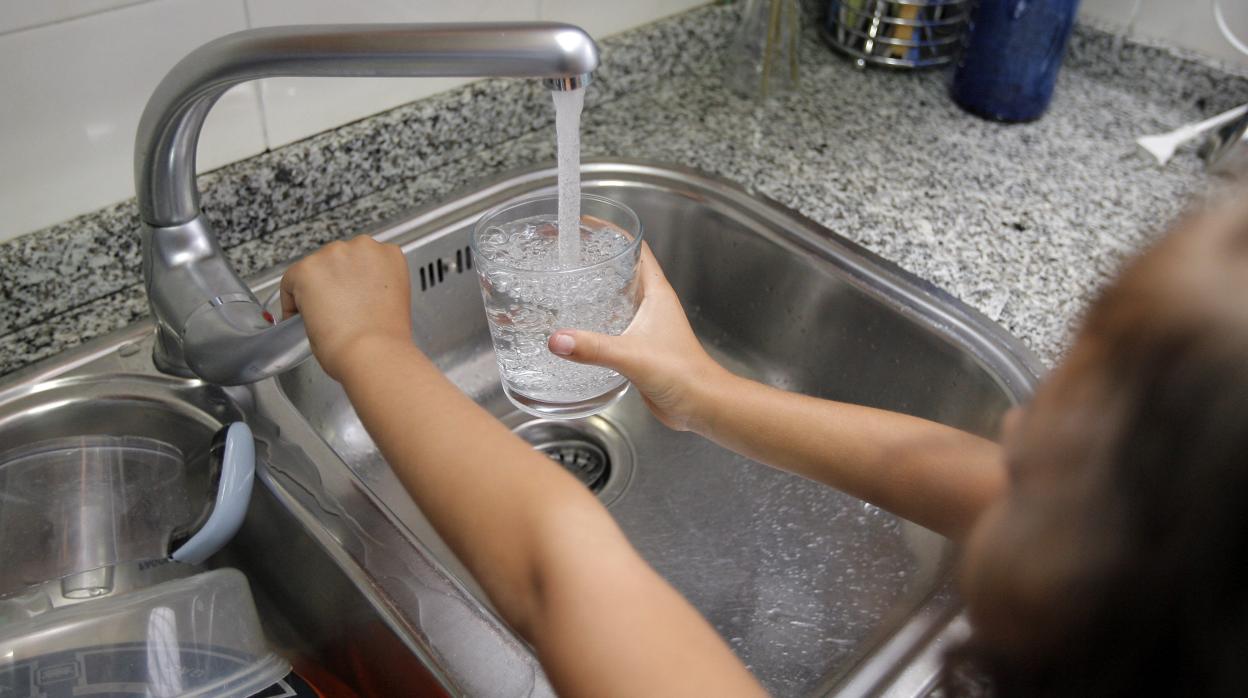 Una niña llena un vaso de agua