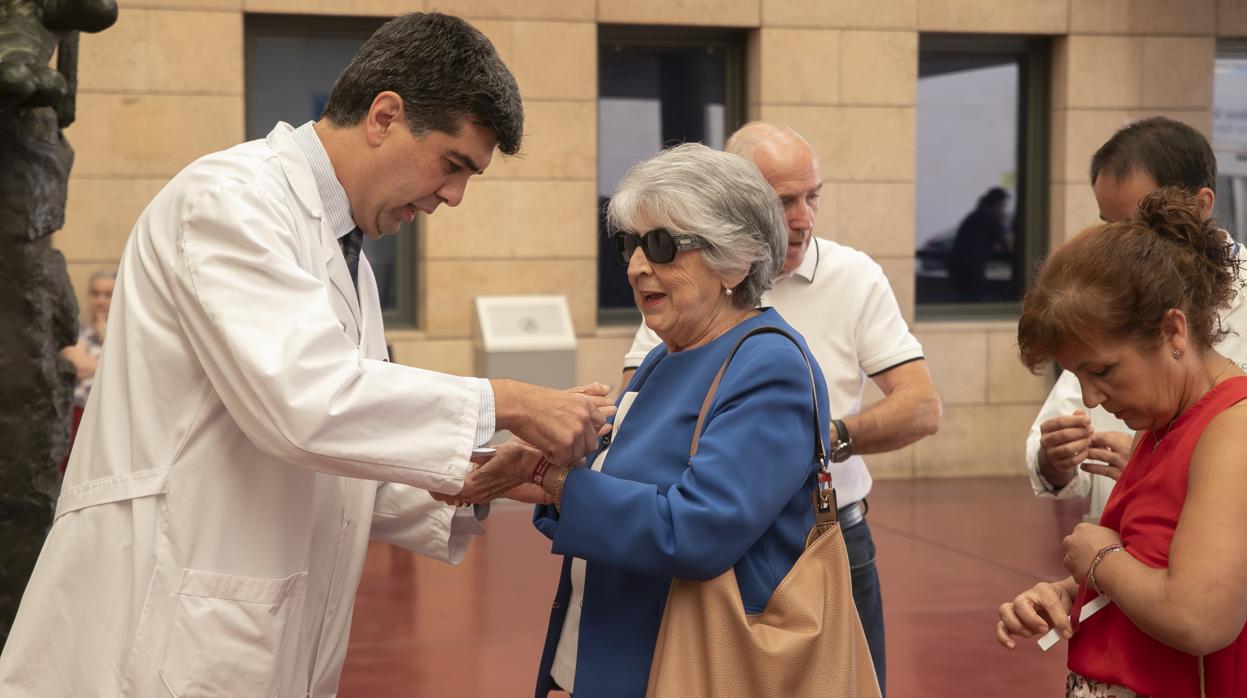 El coordinador de trasplantes coloca a María del Carmen Pinillos la pulsera del 40 aniversario