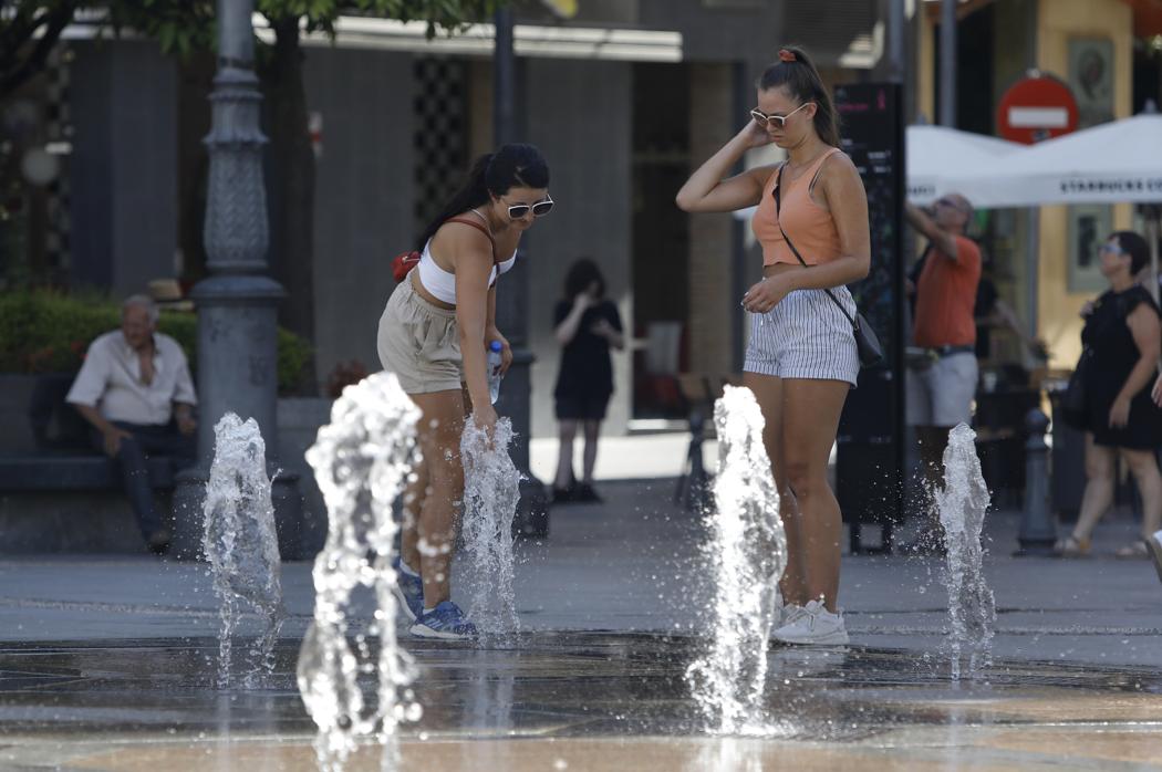 Dos jóvenes se refrescan en una fuente pública de la ciudad