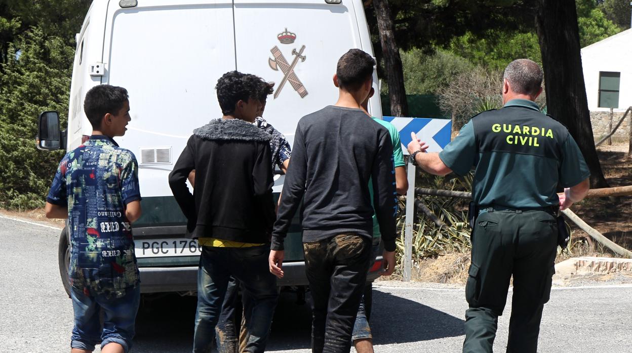 Un agente de la Guardia Civil acompaña a varios menores inmigrantes