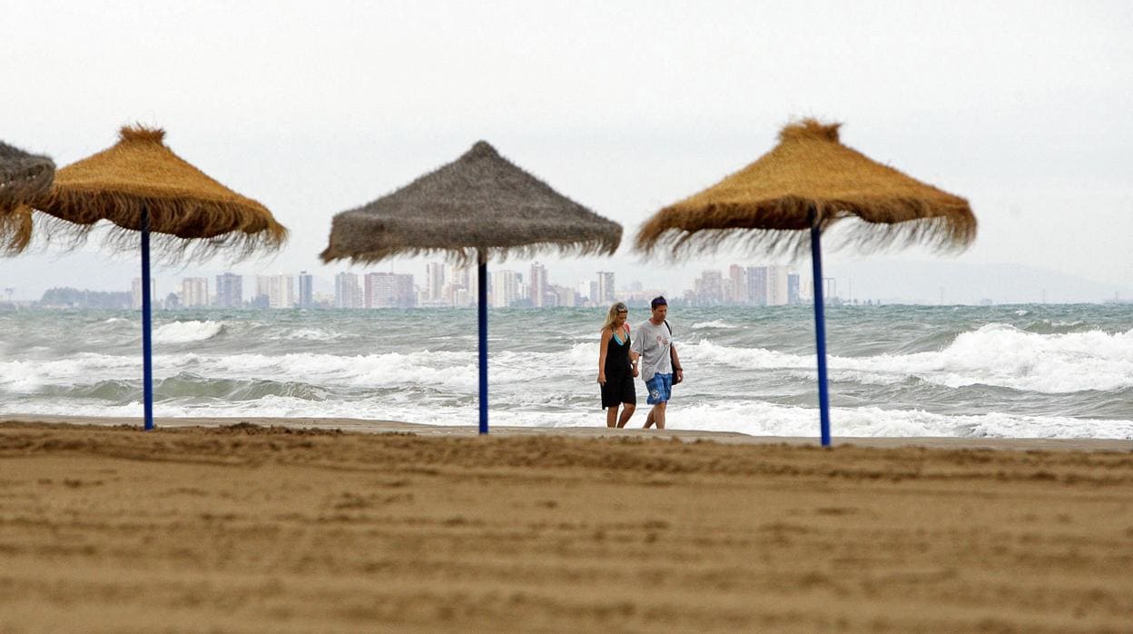Una pareja pasea por una playa en una imagen de archivo