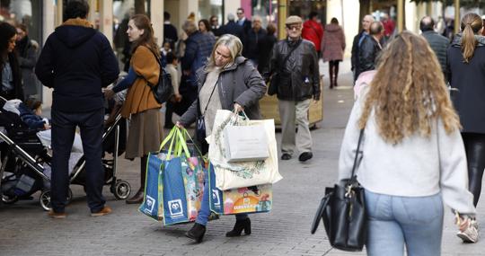 Una mujer cargada de bolsas pasa por la calle Cruz Conde