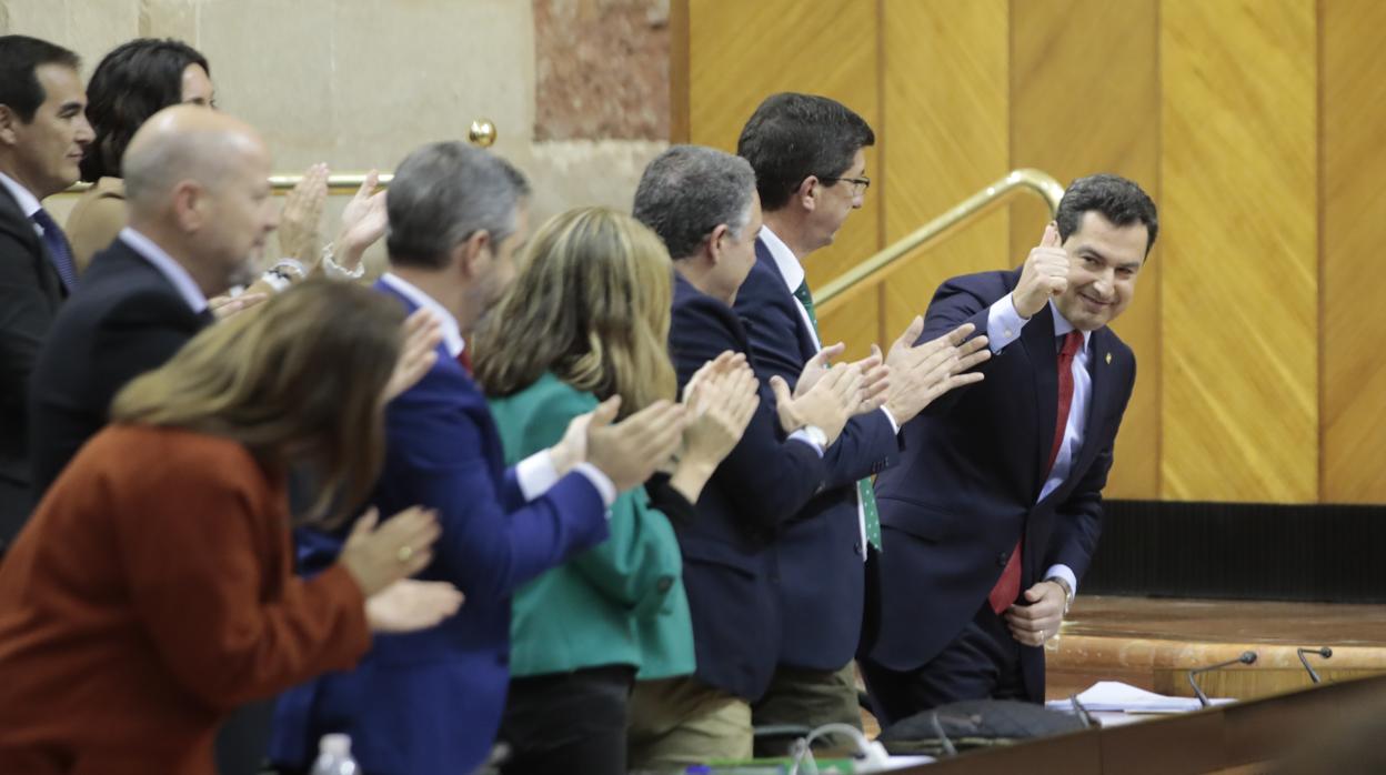 El presidente andaluz, Juanma Moreno, agradece los aplausos a los consejeros de su Gobierno tras su intervención ante el Parlamento