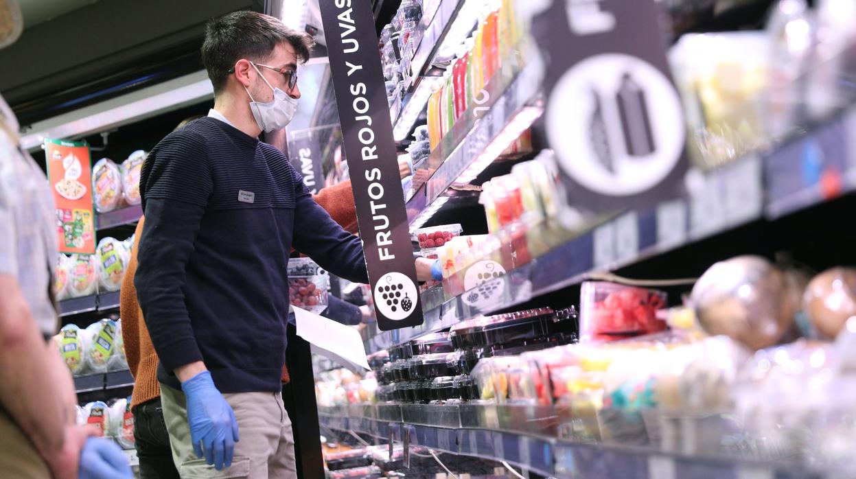 Clientes con guantes y mascarillas en un supermercado