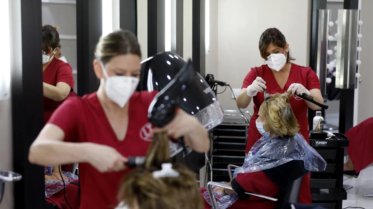Dos empleadas de una peluquería en Córdoba trabajando con mascarilla