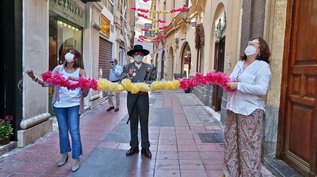 El sastre de la calle Marroquíez, vestido de corto y con mascarilla junto a comerciantes de la calle Barqueros