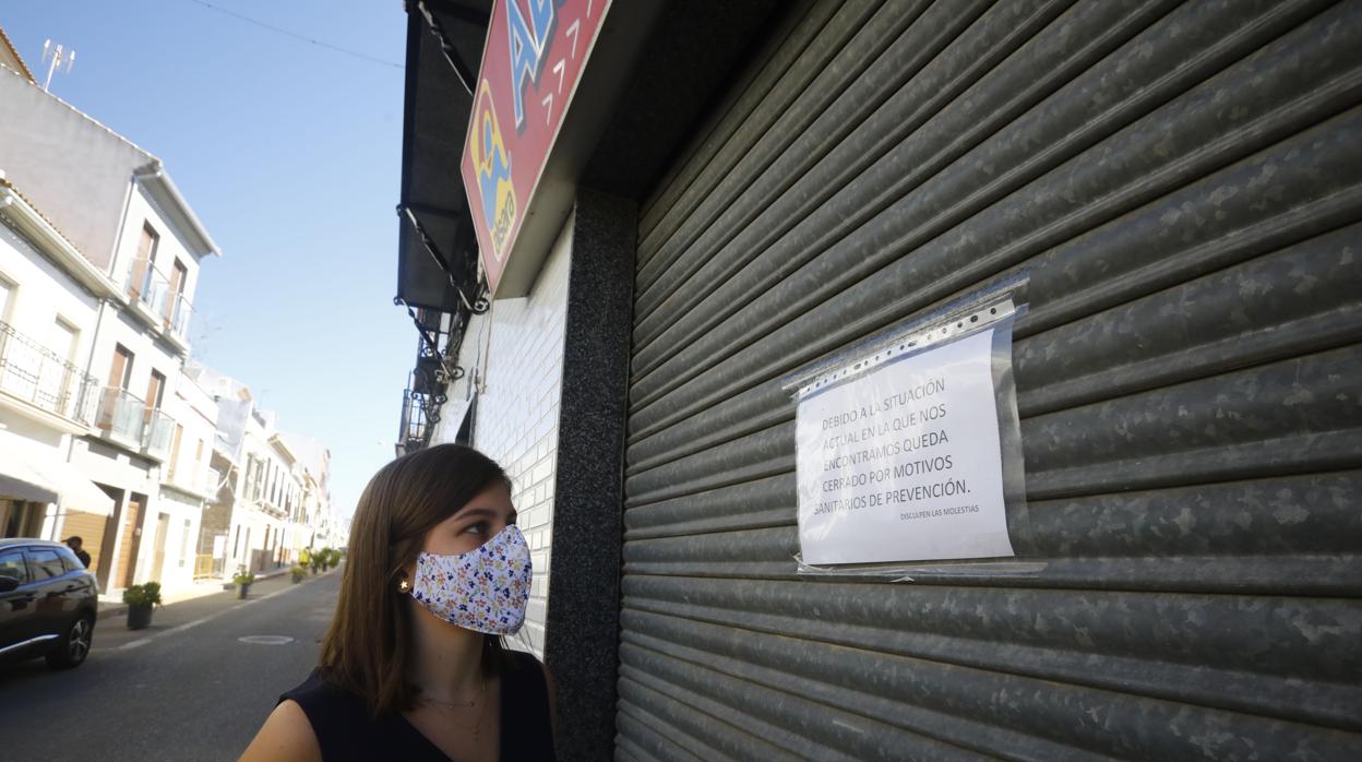 Un mujer mira el cartel de cierre de un supermercado en Montalbán