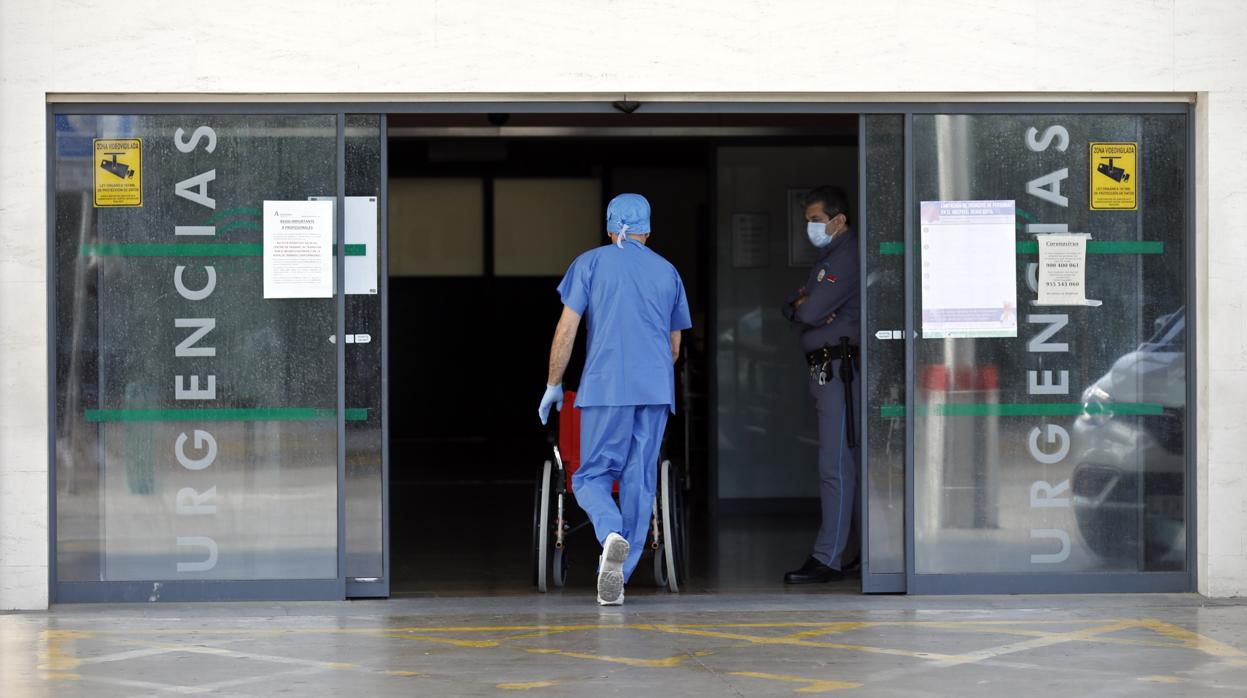 Un sanitario entra con una silla de rueda a Urgencia en el hospital Reina Sofía