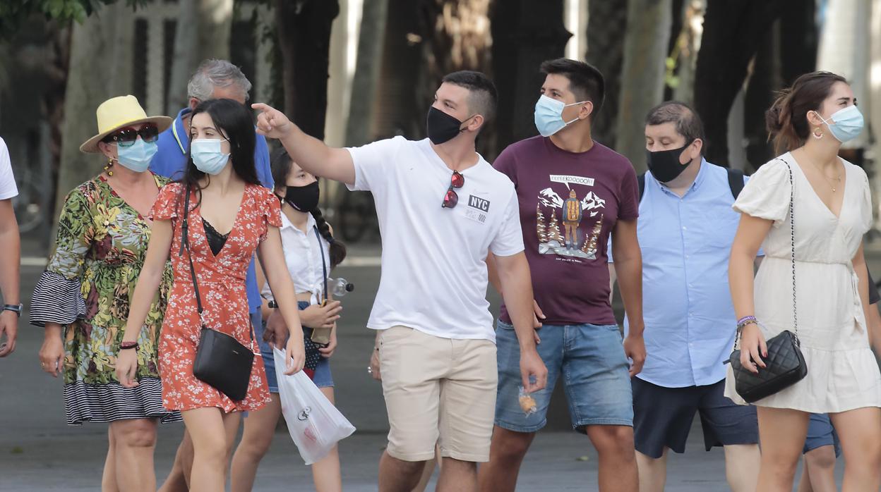 Un grupo de personas pasea por el centro de Sevilla con mascarilla