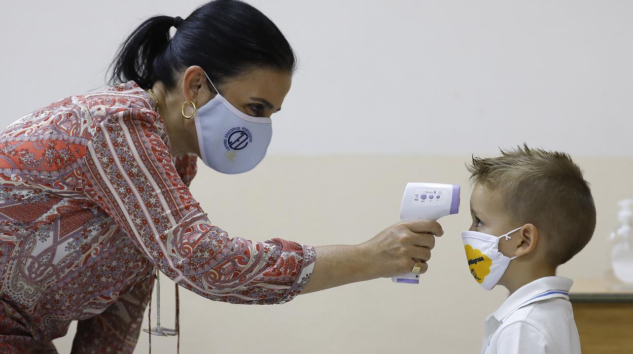 Una profesora toma la temperatura a un alumno antes de entrar en clase