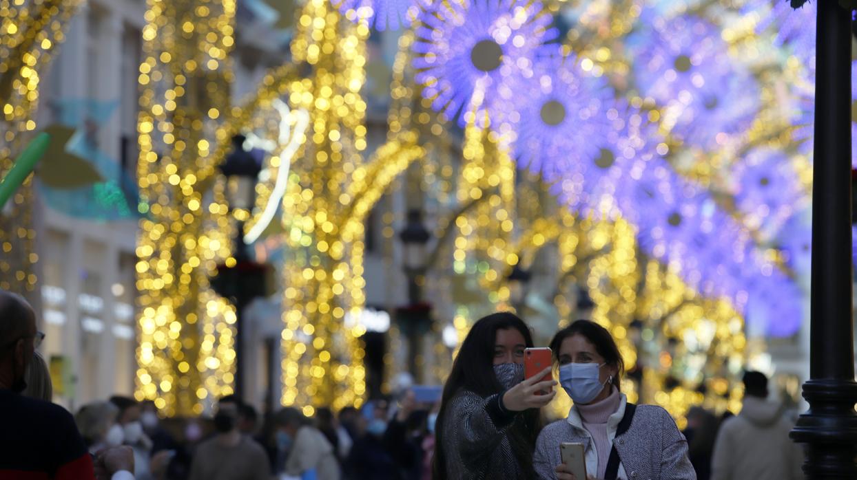 Dos mujeres se retratan en una abarrotada calle Larios de Málaga con motivo de las luces de Navidad