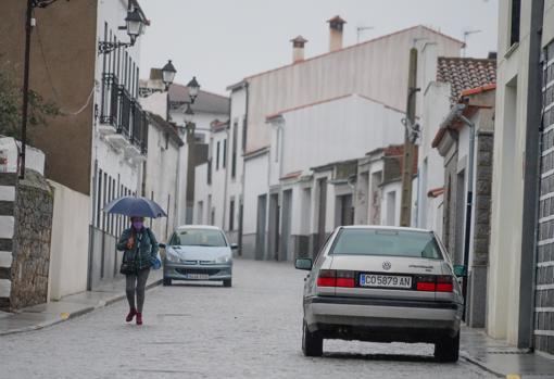 Una mujer camina bajo la lluvia por una calle de Añora
