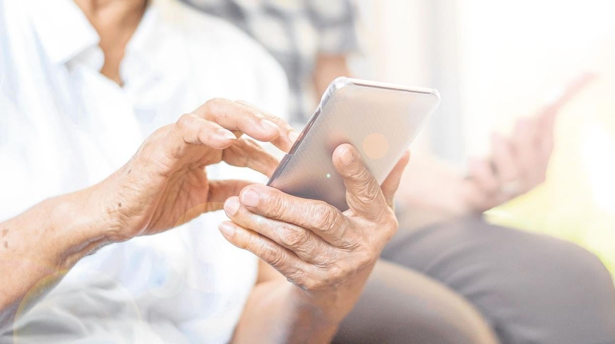 Un hombre mayor sostiene un teléfono móvil