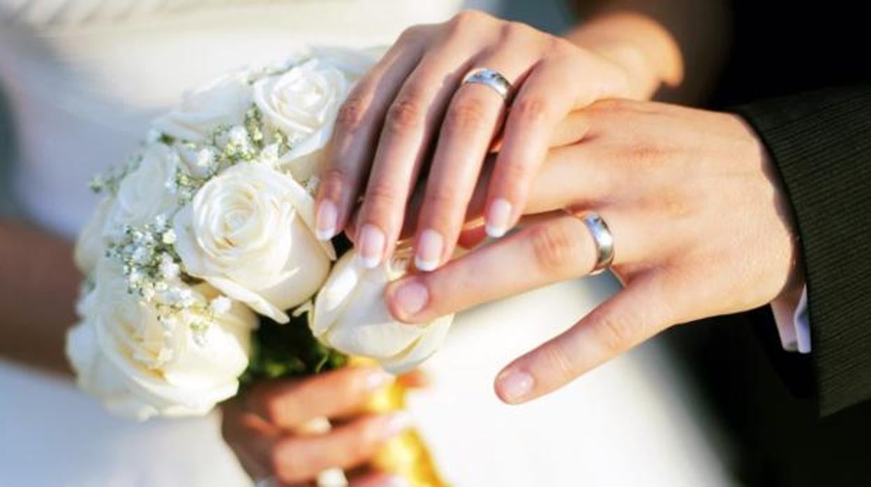 Dos novios muestran su alianza de boda