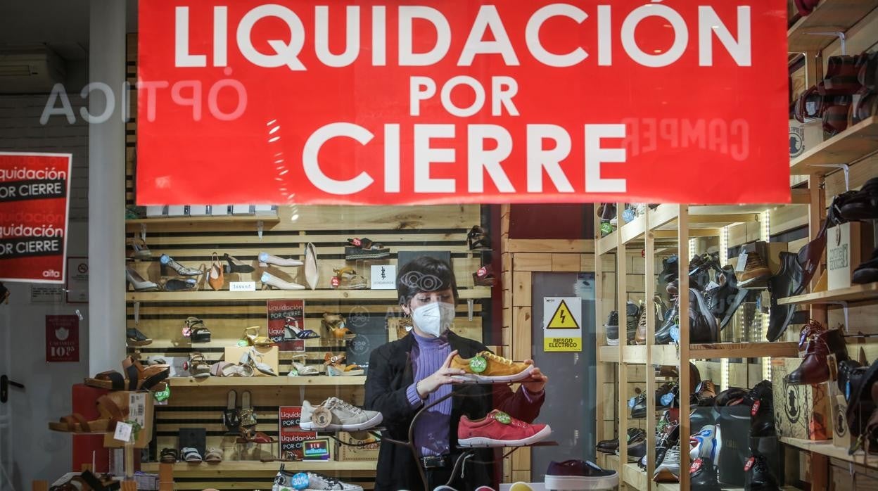 Una mujer cierra la persiana de su negocio