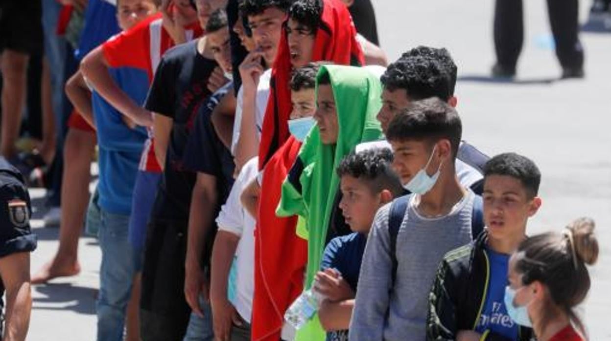 Los menores acogidos en Ceuta hacen una fila preparados para su traslado desde las naves junto a la playa del Tarajal