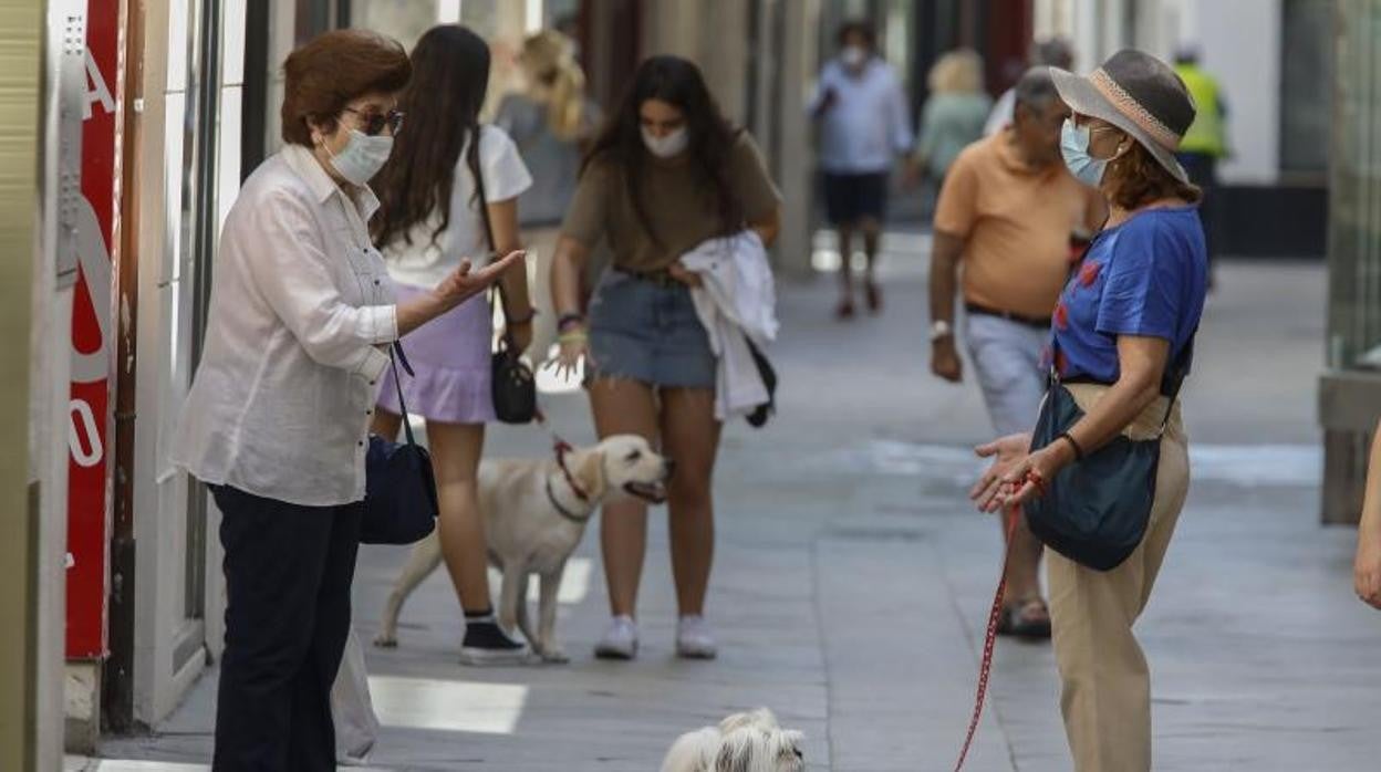 Dos mujeres pasean con sus mascarillas por las calles de Sevilla manteniendo además la distancia de seguridad