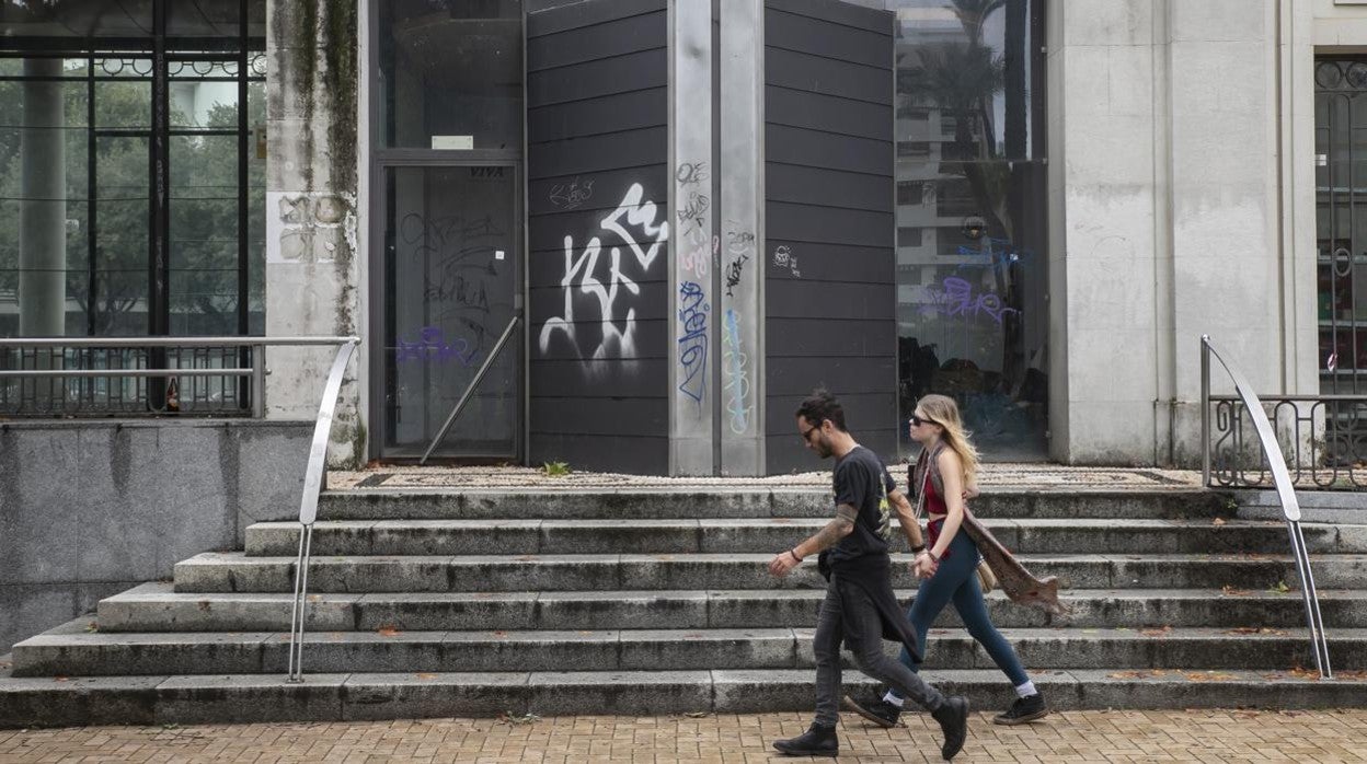 Una pareja pasa delante de la entrada de la Pérgola, donde son evidentes las señales de deterioro y abandono