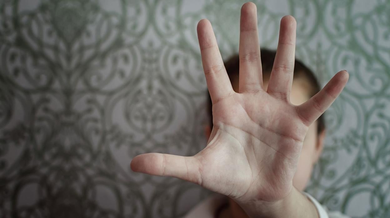 Una chica trata de parar un golpe con la mano