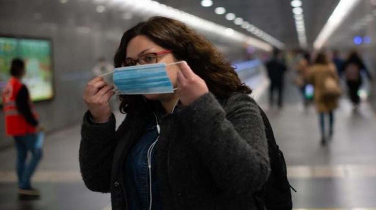 Una mujer se pone la mascarilla