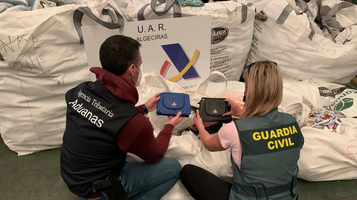 Un agente de Aduanas y otra de la Guardia Civil inspeccionan la mercancía intervenida